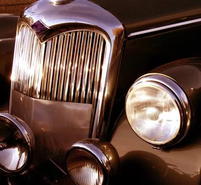 The front grill and headlight of the old beautiful car on the background co.. Stock Photos