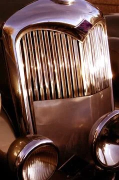 The front grill and headlight of the old beautiful car on the background co.. Stock Photos