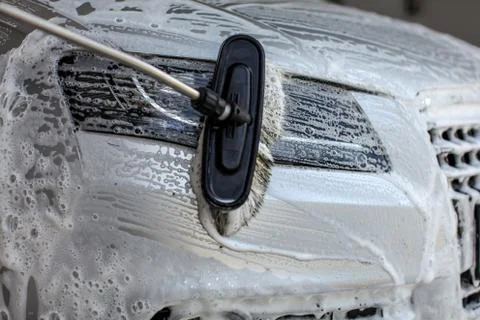 Front headlight being washed in self service carwash. Brush leaving strokes i Stock Photos