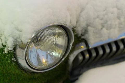 Front headlight of an old car in winter. overgrown with moss. Snowfall Stock Photos
