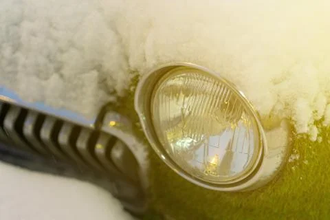 Front headlight of an old car in winter. overgrown with moss. Snowfall Stock Photos