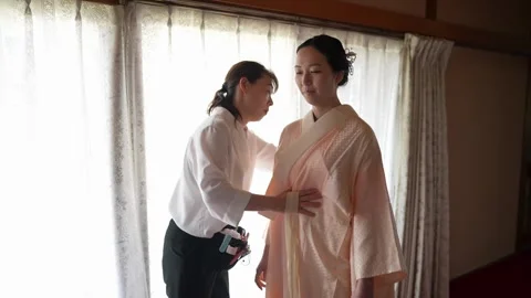 Front layers of a pale kimono adjusted by hand 스톡 동영상 344013542