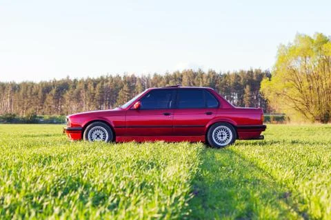 Front left side of an old German car that stands on green grass at sunset Stock Photos