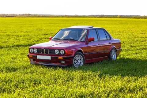 Front left side of an old German car that stands on green grass at sunset Foto stock