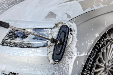 Front light of silver car washed with brush in self serve carwash. Foto stock