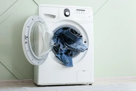 Front load washing machine with denim jeans inside Stock Photos