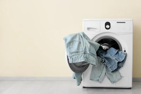 Front load washing machine with denim clothes inside Stock Photos