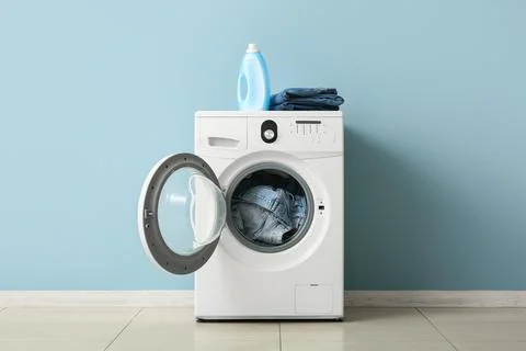 Front load washing machine with denim clothes and detergent Stock Photos