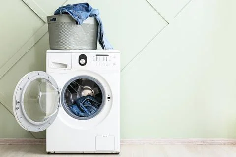 Front load washing machine with denim clothes and laundry basket Stock Photos