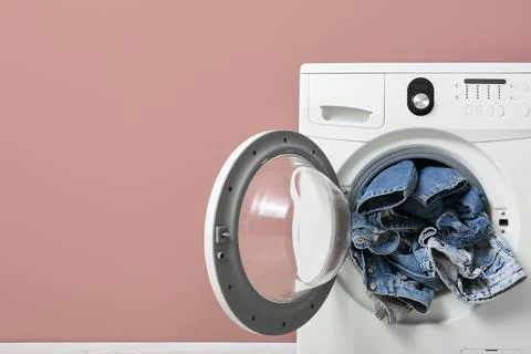 Front load washing machine with denim clothes inside Stock Photos