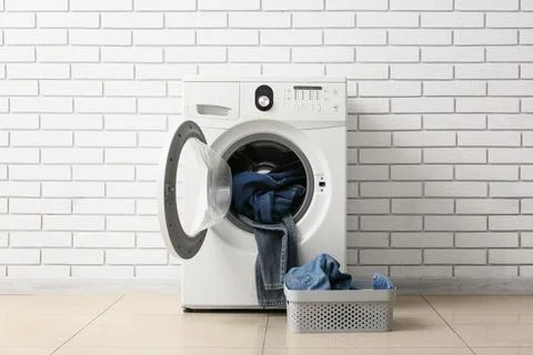 Front load washing machine with denim jeans and laundry basket Stock Photos