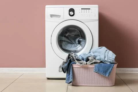 Front load washing machine with laundry basket full of clothes Stock Photos