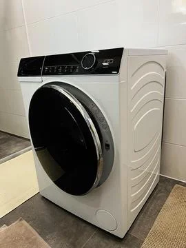 Front load washing machine in modern laundry room with white tiles and chro.. Stock Photos