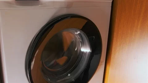 Front load washing machine running spin cycle, drum rotating behind glass door Stock-Footage 333478677