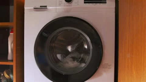 Front load washing machine running rinse cycle, water moving inside rotating Stock-Footage 333478755