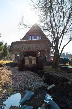 Front loader tips crushed stone at chalet style house construction Stock Photos