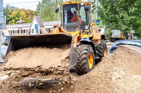 Front loader unload sand at a construction site on the city street Stock Photos