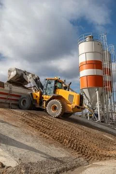 The front loader unloads the crushed stone into the making machine concrete.. Stock Photos