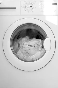 Front-loading washing machine with a transparent door displaying white laun.. Stock Photos