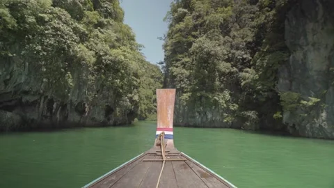 Front of long tail boat floating on water going to defile between mountain Stock Footage 141184497