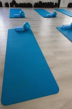 Front-most blue exercise mat is extending into studio, with foam block and blue Stock Photos