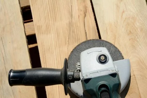 Front part of angle grinder with abrasive disc on planks after work. Stock Photos