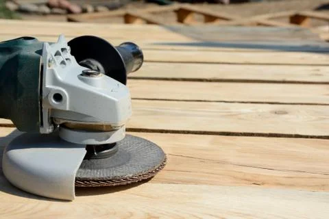 Front part of angle grinder with abrasive disc on planks after work. Stock Photos