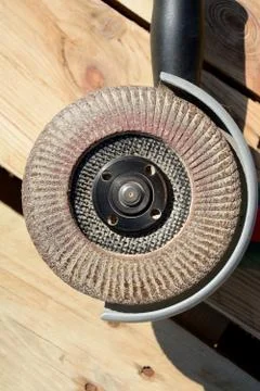 Front part of angle grinder with abrasive disc on planks after work. Stock Photos