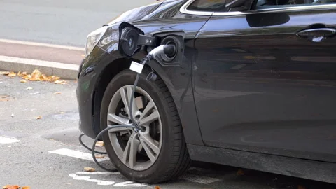 Front part of an electric car plugged and charging at a charge station in France Stock Footage 220773517