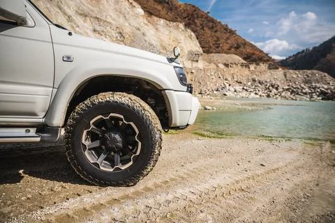 Front part with mud tire of white off-road car in mountain road Stock Photos