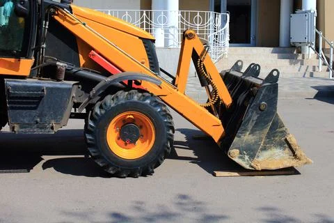 The front part of wheel loader bulldozer with dirty bucket on repair site in Stock Photos