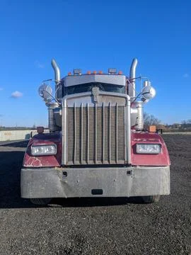The Front of a Powerful Big Rig Red Semi Truck with Chrome Grill Stock Photos