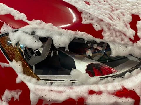 Front right wheel of a red car on which foam is applied to wash a car at a se Stock Photos