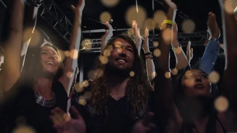 Front-row fans raising hands, clapping at concert, bokeh sweeping crowd as live Stock Footage 331349754