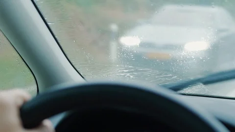 Front screen with rain drops on driving car, traffic meeting Stock Footage 113689015