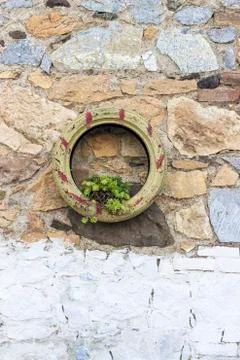 Front shoot of masonry stone wall hanged green colored painted tyre Stock Photos