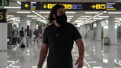 Front shot of a middle aged man walking through the airport terminal carrying Video stock 136393604