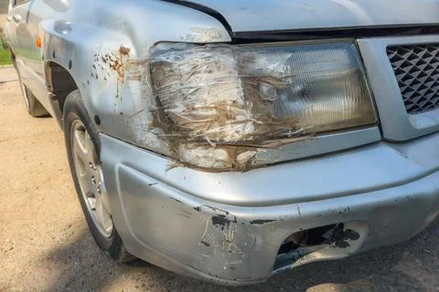 Front side of an old damaged silver vehicle headlamp fixed with clear tape Фото