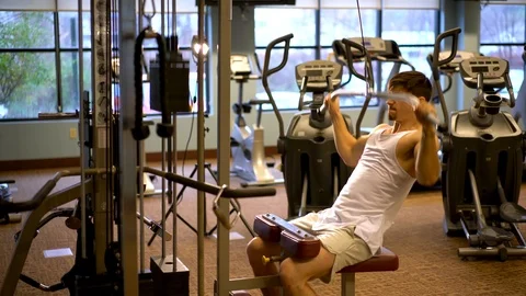 Front side shot of young bodybuilder doing lat pulldowns on a machine. Stock Footage 98288781