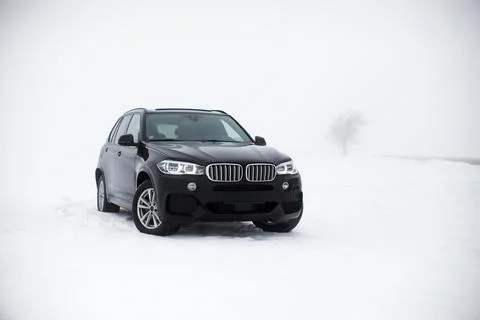 Front side view of a black modern German SUV drifting across pristine white snow Stock Photos