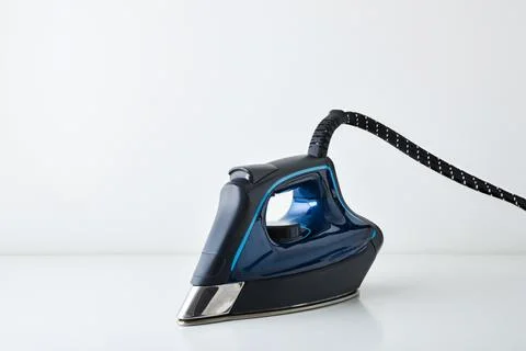 Front side view of blue steam iron reflected on table Stock Photos