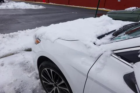 Front side of a white car partially covered by snow Stock Photos