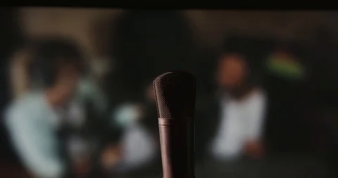 In front of a studio microphone with the producers in the window in the back Stock Footage 99916670