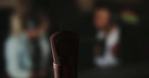 In front of a studio microphone with the producers in the window in the back Stock Footage 99916675