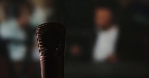 In front of a studio microphone with the producers in the window in the back Stock Footage 99916682