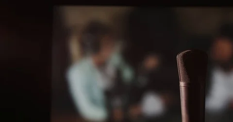 In front of a studio microphone with the producers in the window in the back Stock Footage 99916695