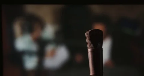 In front of a studio microphone with the producers in the window in the back Stock Footage 99916698