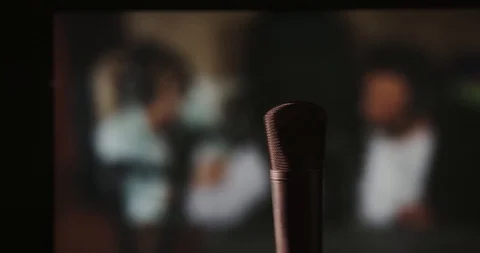 In front of a studio microphone with the producers in the window in the back Stock Footage 99916712