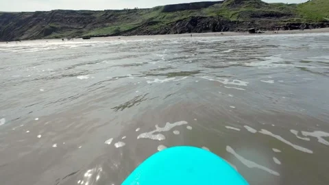 Front of surfboard riding a wave in towards beach Stock Footage 272589881