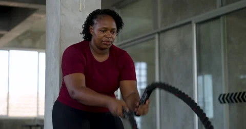 Front view of African American plus size woman making battle rope waves in 库存影片 337647028